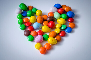 small multi-colored sweets in the form of a heart on a white background