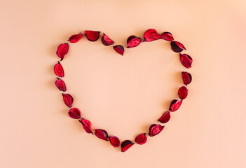 Heart of red petals on coral background. Beautiful frame in shape of heart. Floral template for Valentine's Day, anniversary, wedding