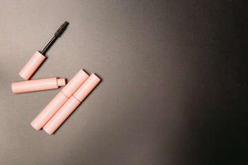pink tube of mascara on a black background, copy space