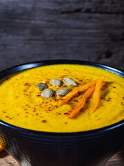 Pumpkin and carrot and chickpeas Cream soup on rustic wooden table.