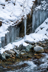 frozen waterfall in the alps hanging from the rocks ata cold winter day