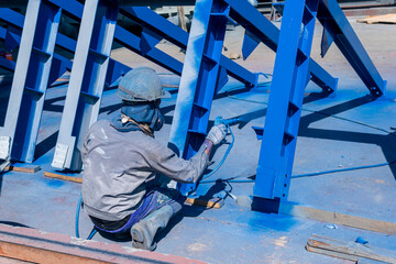 The painter uses a spray gun to paint a steel structure before transportation to the assembly yard.