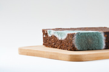 Pumpernickel bread with mold placed on wooden cutting board. Isolated.