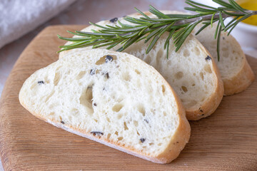 sliced wheat ciabatta with olives on a white towel. Wheat homemade bread, olive oil and rosemary