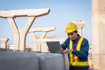 Male engineer working on a laptop computer at a highway construction site