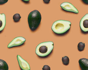 Avocado seamless pattern. Flat lay of whole and half avocados, avacado pieces and seeds. Background made from isolated avocado pieces on orange background.
