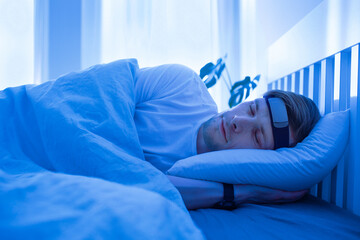Man sleeping on bed with smart sleep headband. Smart sleep tracker. Heartbeat monitor on head. Modern male health monitor. Cozy sleeping bed room. Wearable technology in a daily life to develop habit
