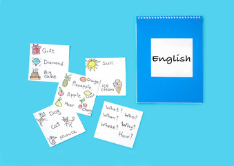 Notepad and cards with words on a blue background. We learn English.