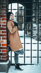 Naklejka premium Zimowy portret kobiety na tle cegły. Portret na tle zamku.
