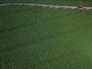 Aerial drone shot of farm machinery spraying agriculture fields in the Suffolk countryside before they harvest