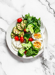 Vegetarian breakfast bowl - salad mixed vegetables, boiled egg, grilled zucchini, cheese on a light background, view over