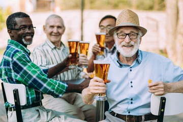 Fototapeta na wymiar Group of senior friends drinking a beer at the park . Old multiethnic friends making activities outdoor. Concept about third age and lifestyle