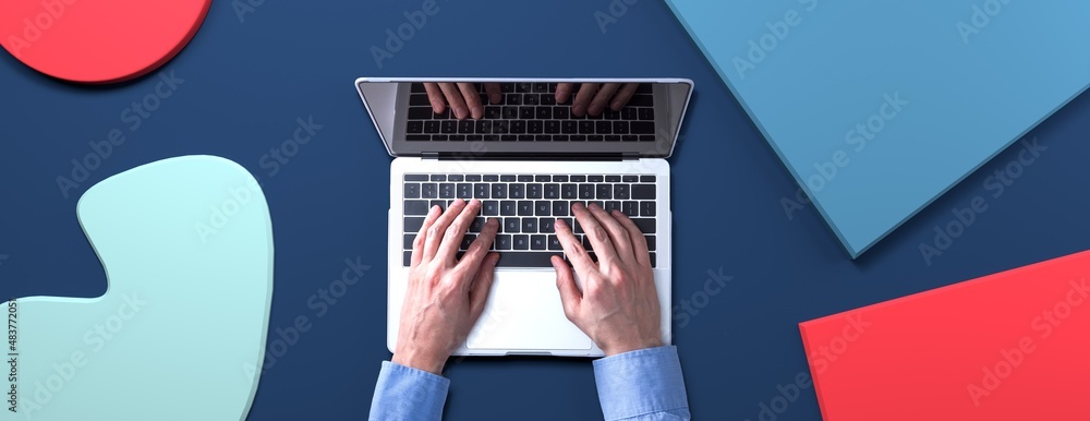 Poster person using a laptop computer with geometric shaped objects from above