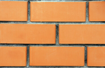 A small part of a close-up of an orange brick wall. Background structure.