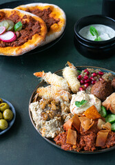 Middle Eastern traditional assorted mezze or meze. Vine leaves, kibbeh, spring rolls, sambusak, kibbeh nayyeh, makdous, haloumi cheese, olives,hummus and yogurt salad.