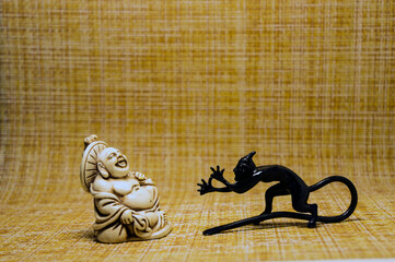 Figurines of a little devil and a laughing monk who look at each other