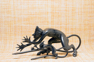 Cast figurines of a small and large devil on a motley background
