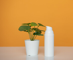 Flacon blanc pour crème de beauté ou produit cosmétique sur fond jaune avec une plante verte - mock up pour texte ou design