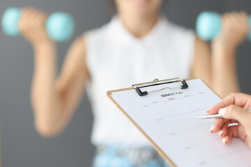 Female hands are writing down a workout plan, motivation