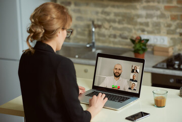 Laptop screen view over a woman's shoulder. A girl works remotely on a computer.