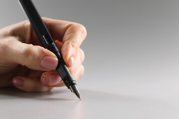 Female fingers hold a black fountain pen, close-up