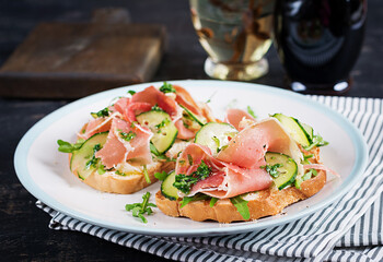 Breakfast or brunch.  Open sandwich with prosciutto or jamon on white plate. Mediterranean appetizer.