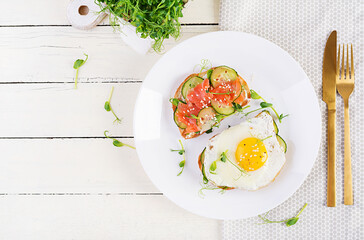 Diet breakfast. Sandwich with salt salmon salad with greens, cucumbers, fried egg and microgreen. ...