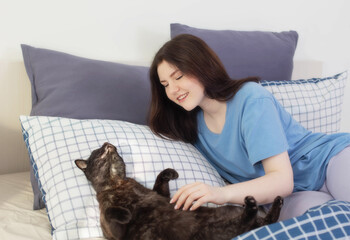 happy teen girl with black cat in white bedroom