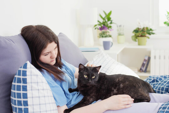 happy teen girl with black cat in white bedroom