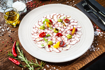 Octopus carpaccio. Spinach cream, cherry tomatoes. Delicious healthy Italian traditional food closeup served for lunch in modern gourmet cuisine restaurant