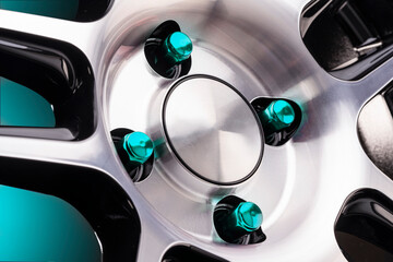 beautiful bright seven-sided car wheel nuts turquoise or green close-up on a sporty style alloy wheel on a black background for auto tuning of a tire and disc store or auto parts