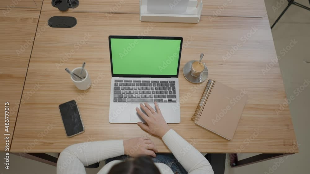 Poster office table with green screen laptop computer and female hands taping or scrolling on pad. notebook