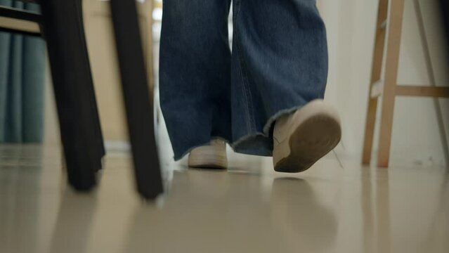 Slow-motion woman's legs in white snickers and jeans walking towards the camera lens  