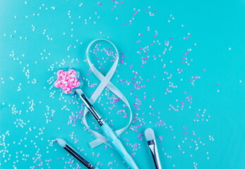 Makeup accessories,brush set,shiny pigment in bottle,gift ribbon on a blue background with glitter,flat layot