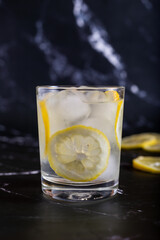Iced glass of water and lemon on a black background