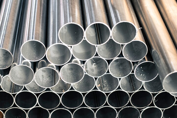 Chrome-plated stainless steel pipes cut on a band saw in a factory, close-up. 