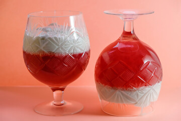 Jelly from redcurrants and sour cream, in crystal glasses on a coral-colored background. 