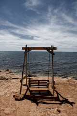 Swing on the shore of the blue sea on the yellow sand