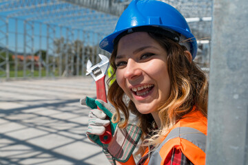 Cheerful construction worker smiling at the camera while sitting. Beautiful young woman, sitting in front of framework of the new building.