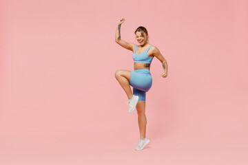 Fototapeta na wymiar Full body young strong sporty athletic fitness trainer instructor woman wear blue tracksuit spend time in home gym do winner gesture isolated on pastel plain pink background. Workout sport concept