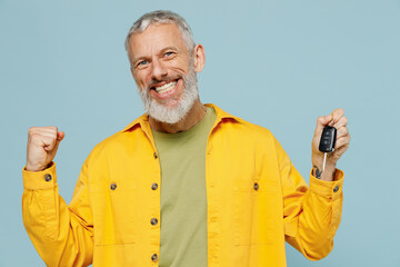 Elderly gray-haired mustache bearded man 50s in yellow shirt hold car keys fob keyless system do winner gesture isolated on plain pastel light blue background studio portrait People lifestyle concept
