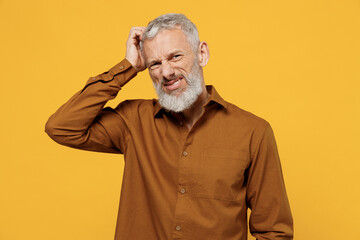 Puzzled thoughtful wistful elderly gray-haired bearded man 40s years old wears brown shirt scratch...