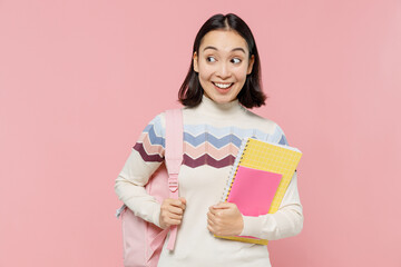 Teen student girl of Asian ethnicity in sweater backpack hold books look aside on workspace area...
