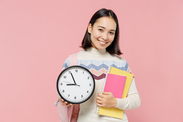 Smiling happy satisfied teen student girl of Asian ethnicity wear sweater backpack hold books clock...