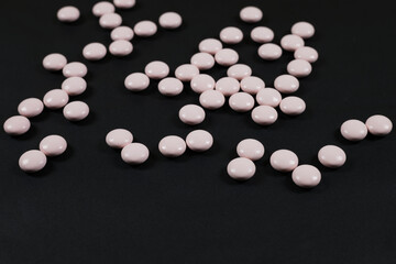 Fototapeta na wymiar light pink pills on a dark background