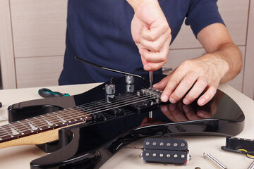 Guitar master adjusts scale on modern electric guitar.