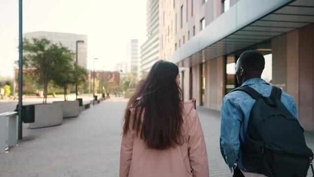 Multiracial traveling couple walking along street