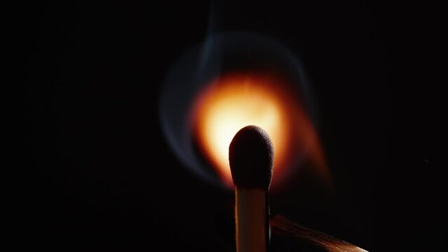 Person igniting matchstick against black background