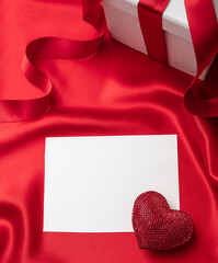Valentine red color ruby heart on empty card on red silk fabric background.