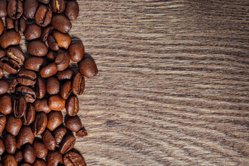 Roasted coffee beans on dark brown wooden table with copy space. Top view on coffee beans on wooden background.